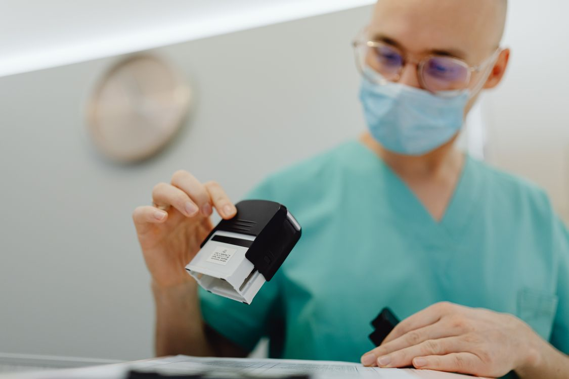 Healthcare professional reviewing and stamping documents representing regulatory compliance and institutional oversight.